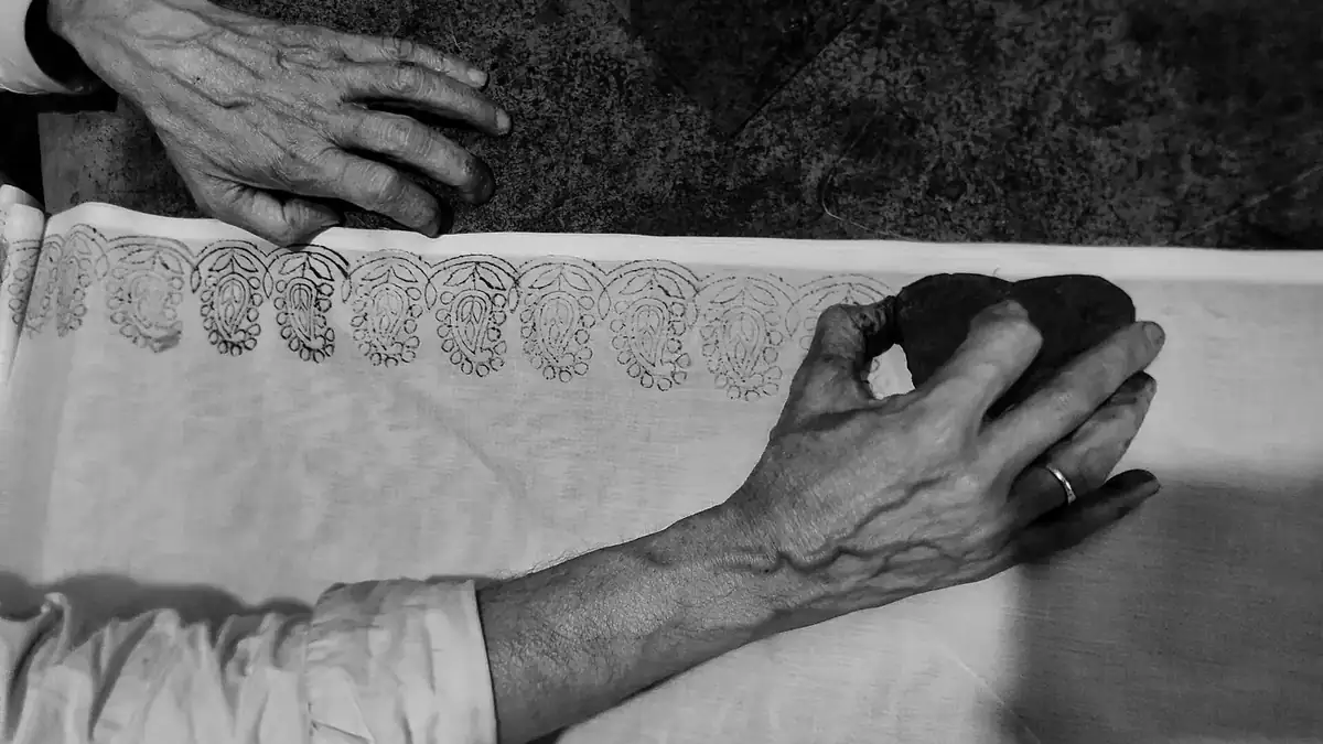 A craftsperson hand block printing a textile