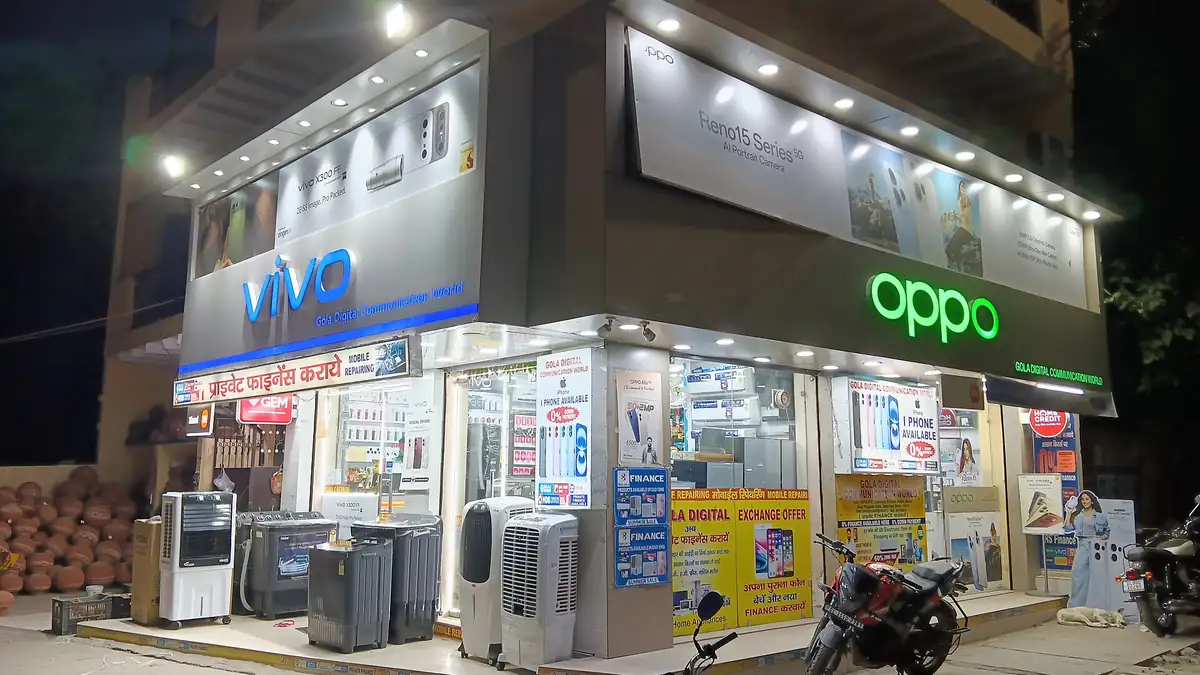 A lit-up mobile phone shop at night in Dabri, Delhi
